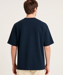 Hombre de espaldas usando camiseta oversized azul marino sin estampado.