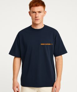 Modelo masculino con camiseta oversized azul marino de Isnach Clothing, logo frontal en naranja; estilo urbano minimalista, ideal para streetwear contemporáneo.