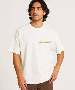 Camiseta oversized blanca con logo Isnach Clothing en naranja, llevada por modelo masculino; look casual moderno perfecto para verano o uso diario.