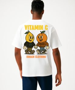 Modelo masculino con camiseta blanca oversized, ilustración trasera de frutas sonrientes y texto “Vitamin C”; diseño colorido de Isnach Clothing.