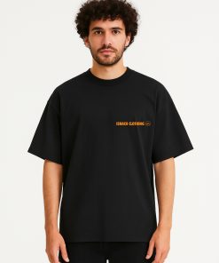 Camiseta negra oversized de Isnach Clothing con logo naranja, llevada por modelo masculino; contraste elegante y diseño versátil para outfits urbanos.