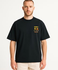 Modelo masculino con camiseta oversized negra, estampado minimalista “Vitamin C” en el pecho; estilo limpio y gráfico con toque juvenil.