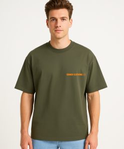 Camiseta oversized verde oliva con logo Isnach Clothing en naranja, usada por modelo masculino; diseño neutro y moderno ideal para combinaciones casuales.