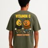 Camiseta oversized verde oliva con frutas animadas y mensaje “Vitamin C” en amarillo; diseño trasero llamativo con firma de Isnach Clothing.