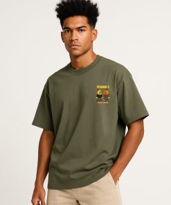 Camiseta oversized verde oliva con mini estampado de personajes frutales y texto “Vitamin C” al frente; estilo divertido, ideal para streetwear.