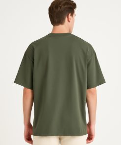 Modelo de espaldas vistiendo camiseta oversized verde sin diseño.