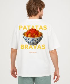 Modelo masculino con camiseta blanca oversized y diseño “PATATAS BRAVAS” en gran formato con bol tradicional español y salsa visible.